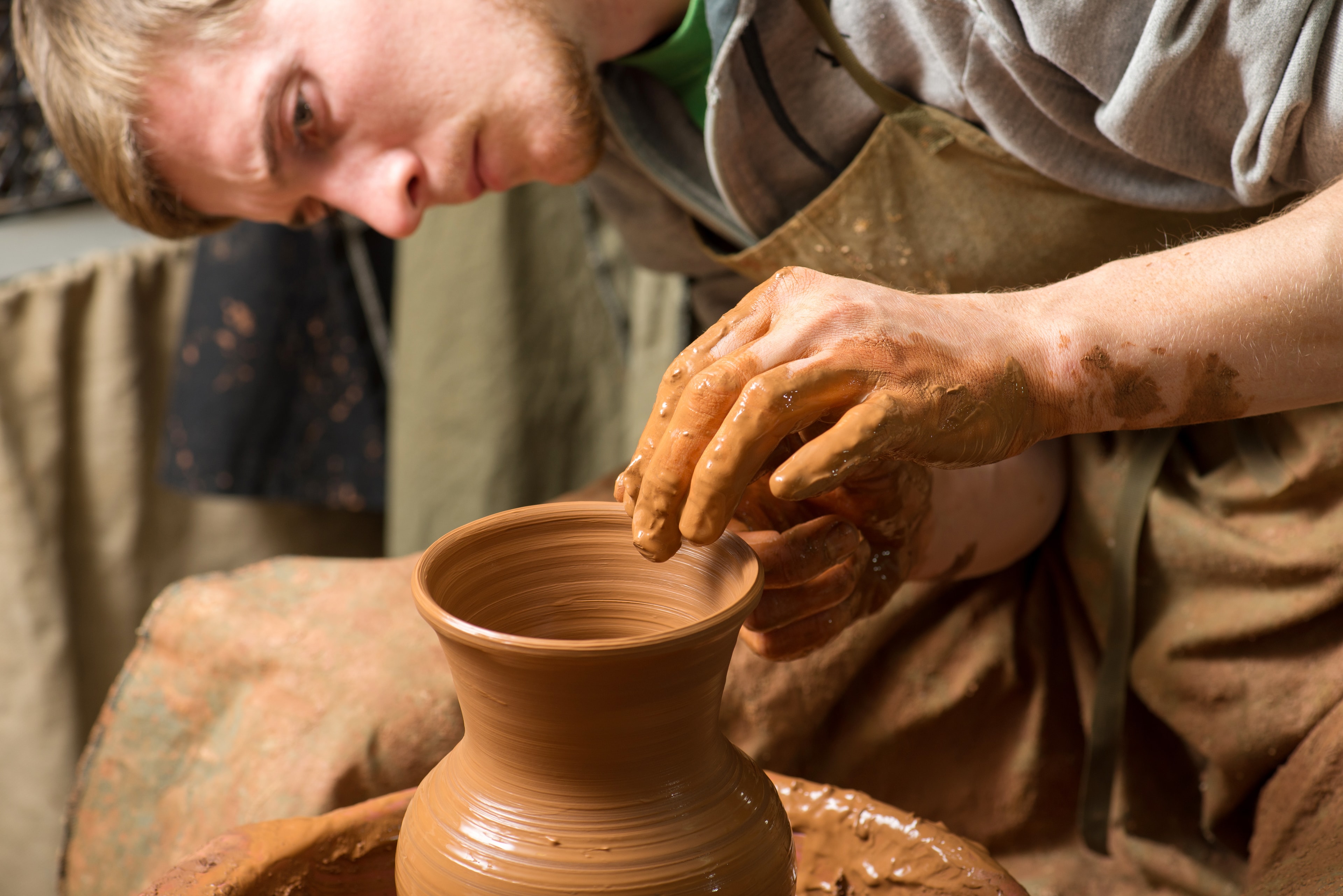 Potter shaping a clay vase on a wheel