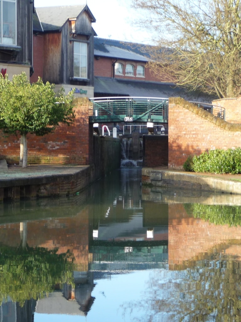 Oxford Canal lock 165 in Banbury town centre, with brick buildings and reflections in the still water, showing the canal route into the heart of the town