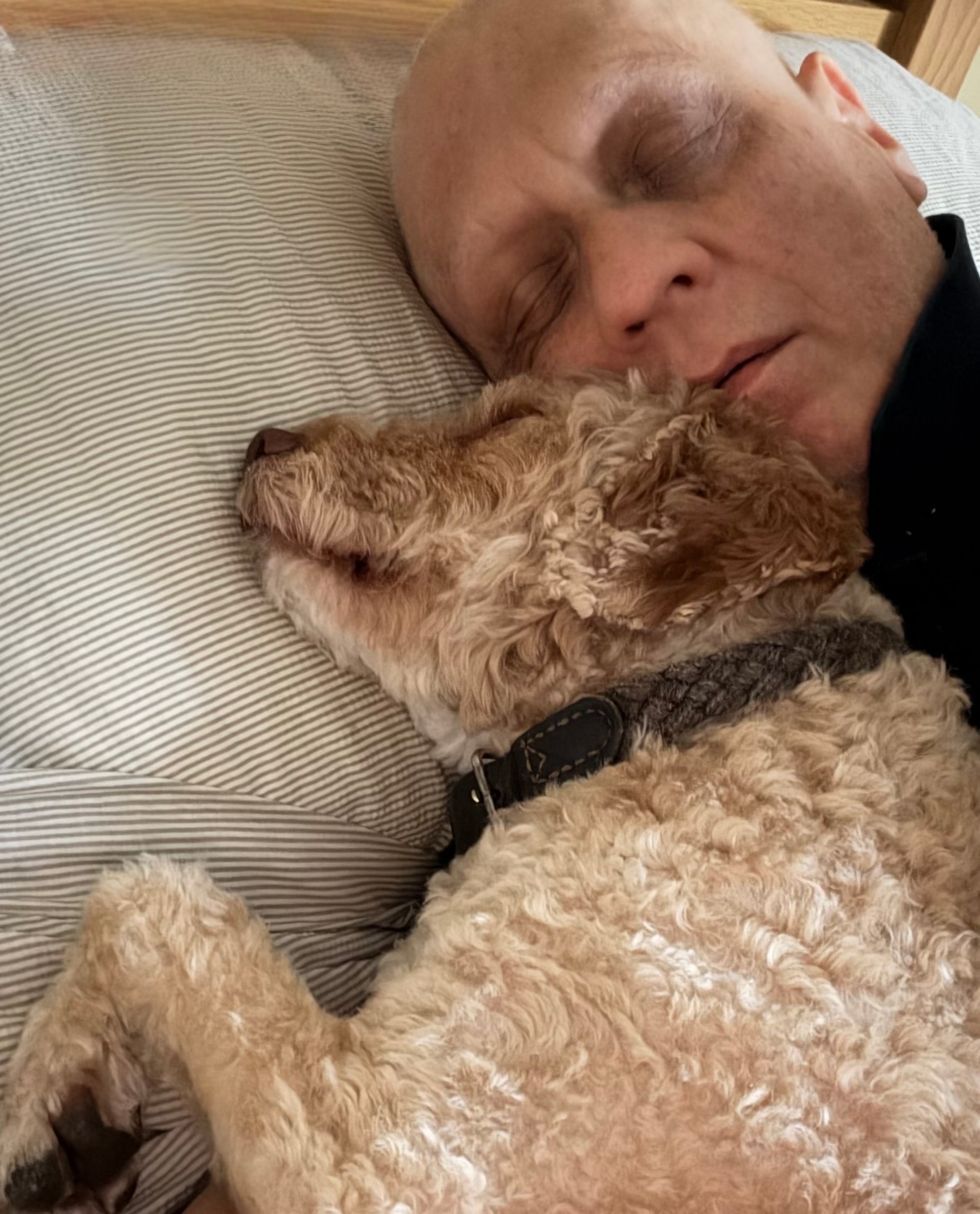 Paul-Austin resting with Woody curled up beside him during his cancer diagnosis